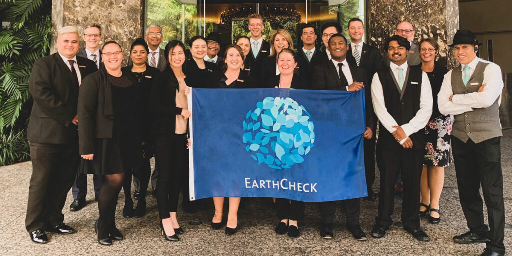Cordis Auckland staff holding EarthCheck flag