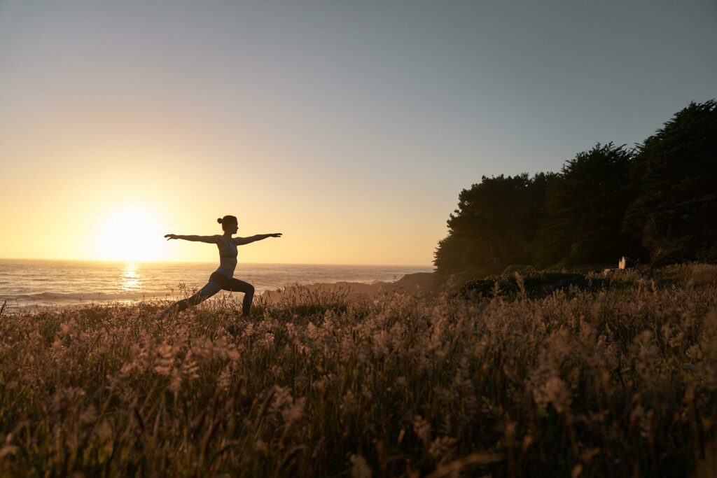 Woman doing yoga at sunrise on the beach