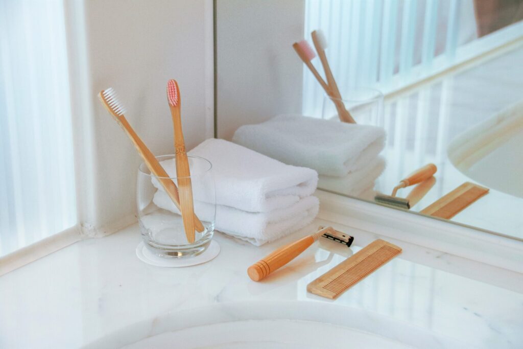 Bamboo toothbrushes, razor and comb sitting beside a bathroom sink