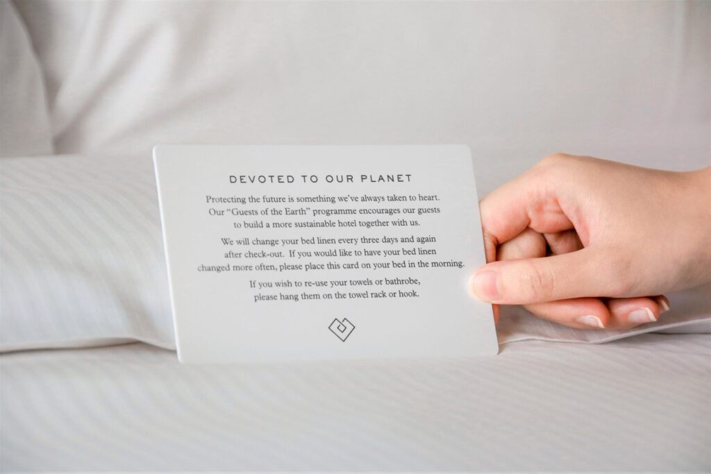 Card outlining environmental practices at EarthCheck being placed on a made bed