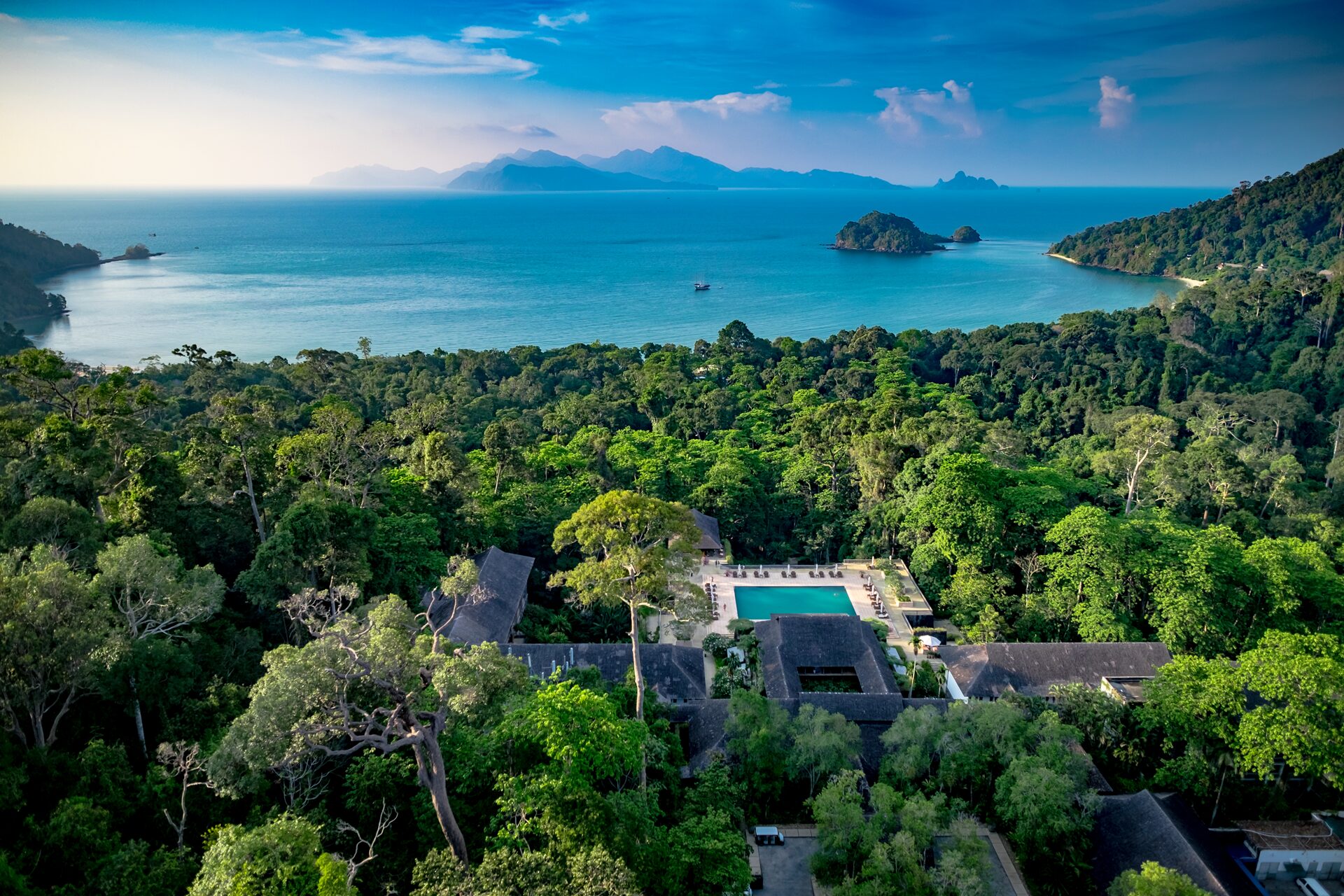 Aerial view over The Datai Langkawi Resort out towards the ocean with mountains in the background