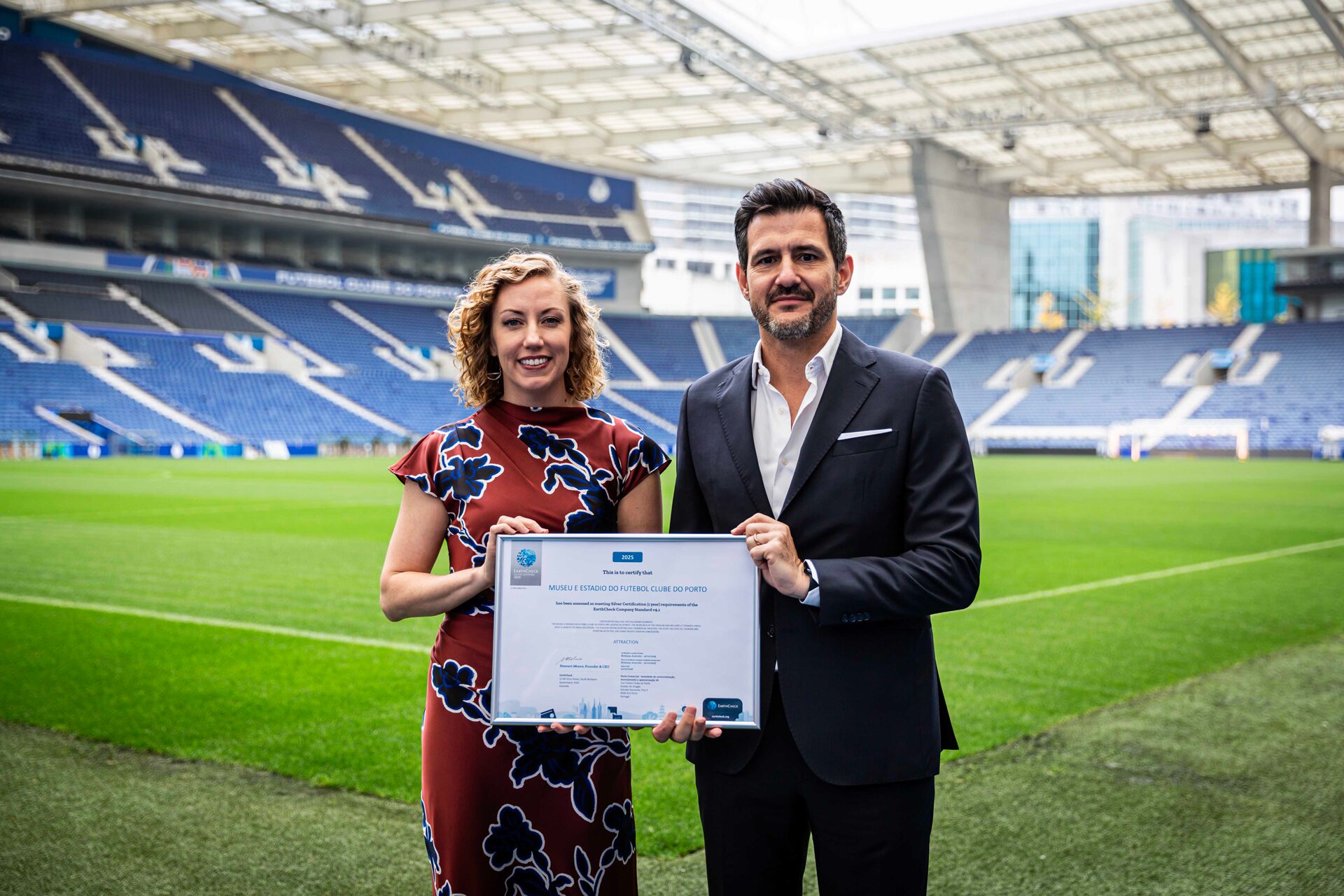 Two people doing a certificate presentation in on a football field in a stadium