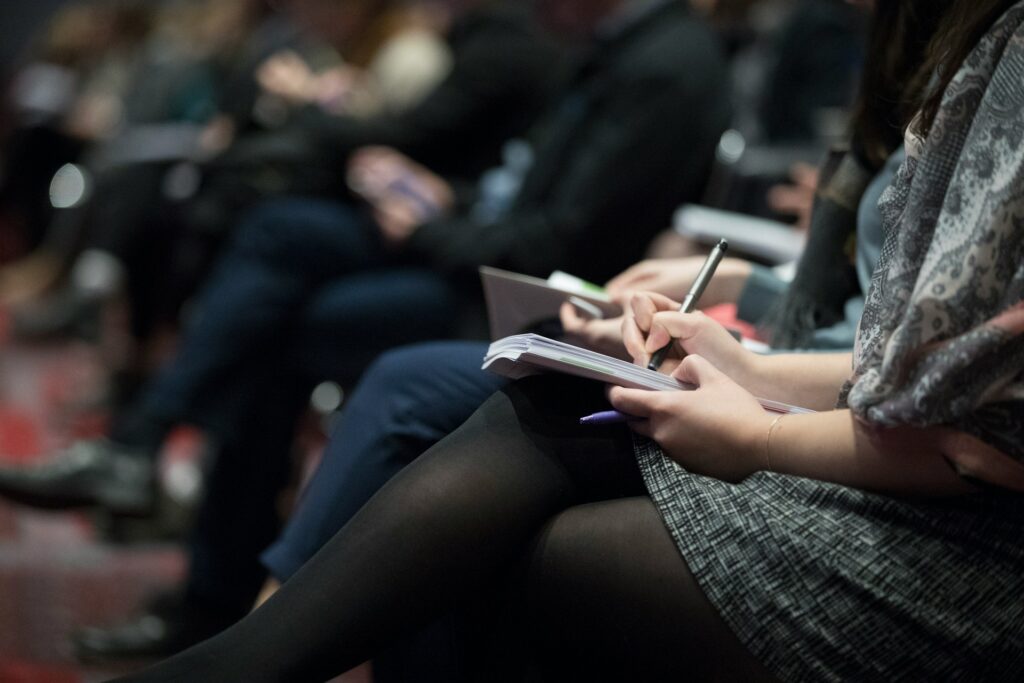 An event attendee sits with notepad and pen in hand