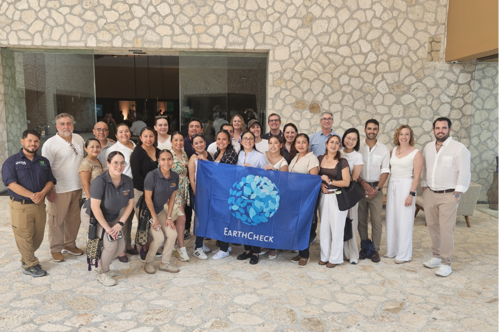 Group of people posing for a photo with the EarthCheck flag